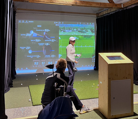 Golfball auf dem Abschlagteppich vor Simulator-Projektion